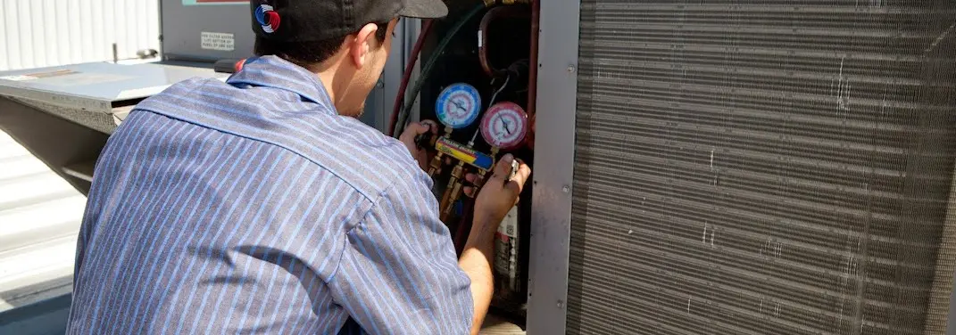 HVAC technician servicing a condenser unit in Battlement Mesa